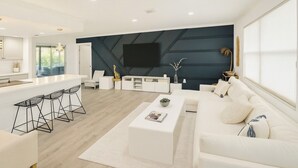 Una sala de estar moderna con sofá, mesa de centro y taburetes de bar.