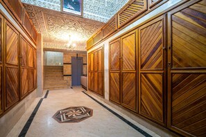 A hallway with ornate wooden paneling, a geometric floor pattern, and a chandelier. - Mira Stay (Marrakech)