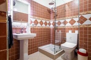 Un baño con ducha, inodoro, lavamanos y espejo.
