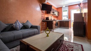 Un salón con sofá, una mesa de centro y una cocina al fondo.