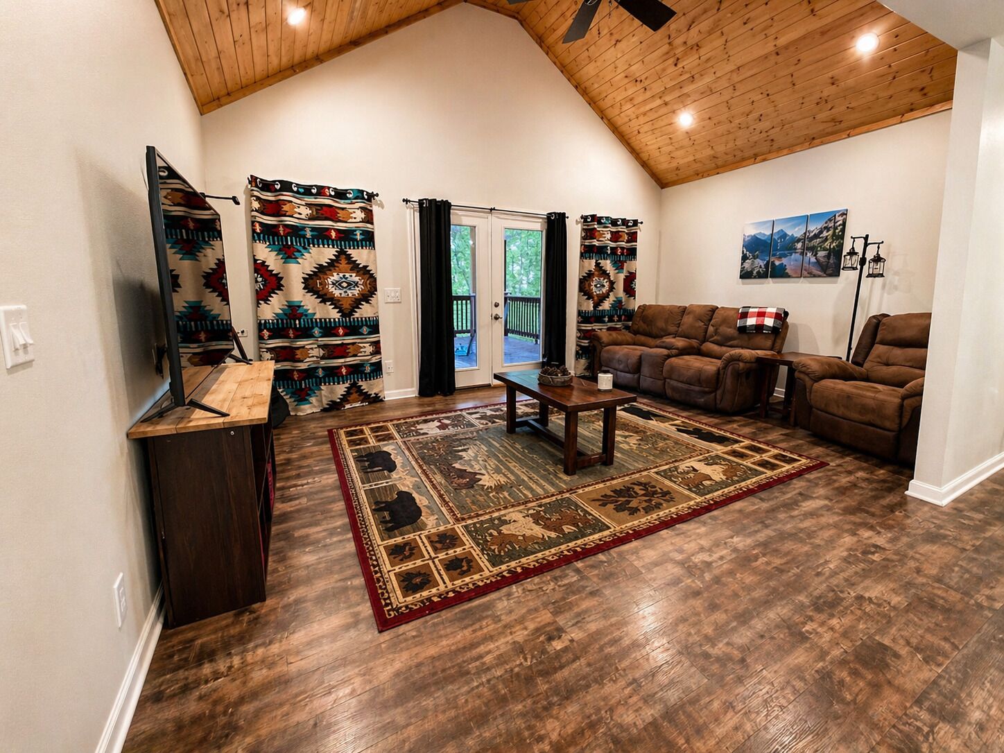 Un salon avec un plafond haut, un plancher en bois, un canapé, une table basse et un téléviseur.