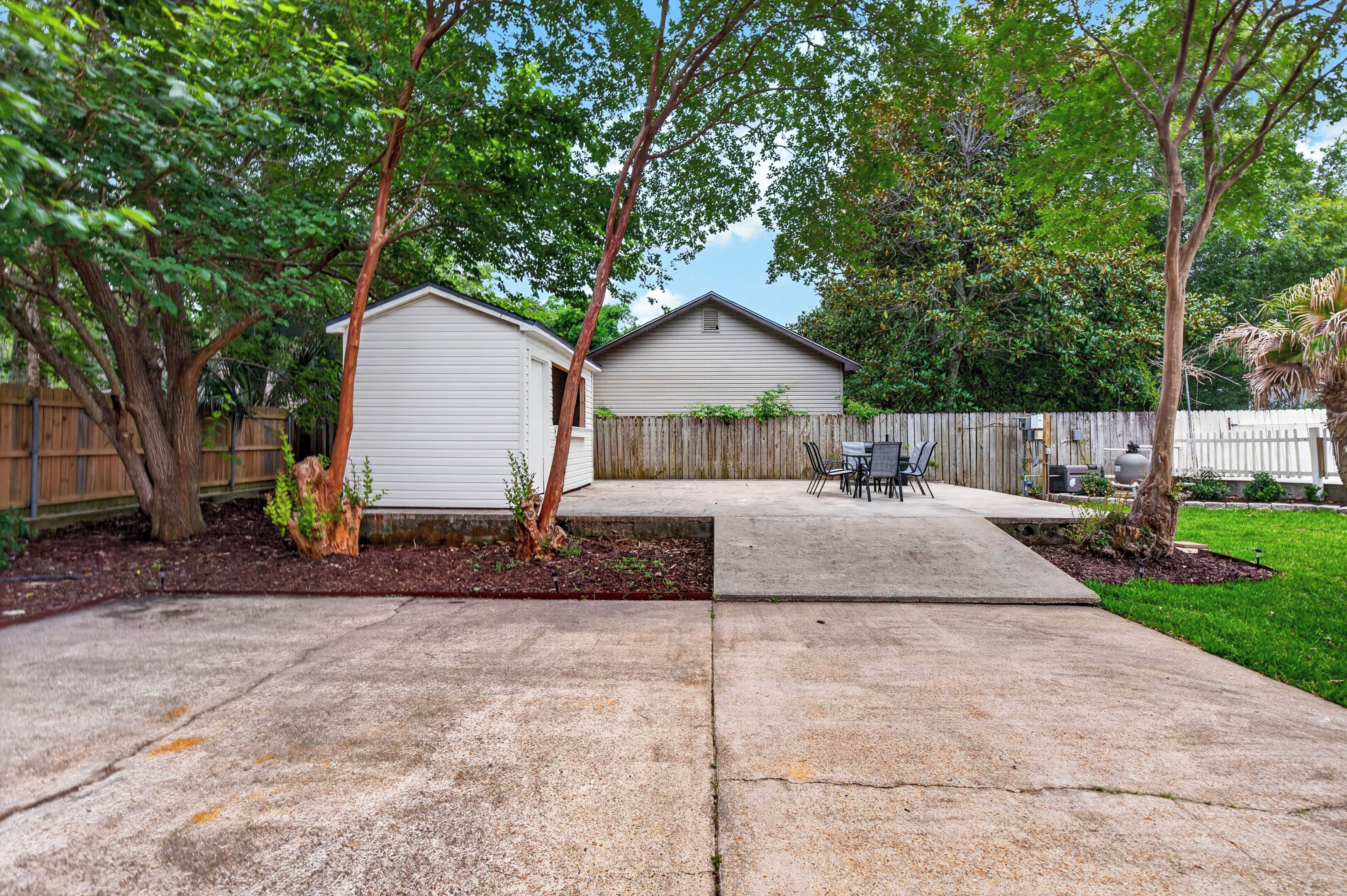 A backyard with a concrete patio, a wooden fence, and a small shed.