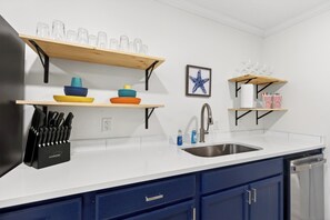 A kitchen with a white countertop, blue cabinets, and various kitchenware on shelves.