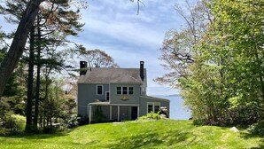 A house with a chimney, a garage, and a view of the water. - Classic Maine Summer Cottage on the Ocean (Boothbay Harbor)