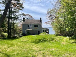 A house with a chimney, a garage, and a view of the water. - Classic Maine Summer Cottage on the Ocean (Boothbay Harbor)
