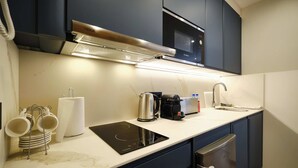 A modern kitchen with a built-in microwave, kettle, coffee maker, and a sink. - Studio Premium Suite Venezia, non-smoking (Avilés)
