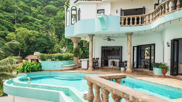 Una casa a due piani con piscina, mobili da esterno e un balcone.