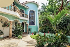 A courtyard with a fountain, a balcony, and lush tropical plants. - Amazing 4-bedroom villa in Puerto Vallarta with full kitchen and pool (Puerto Vallarta)