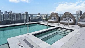 Uma área de piscina no terraço com vista desobstruída da linha do horizonte da cidade, incluindo um edifício com a inscrição 'RENT 305'.