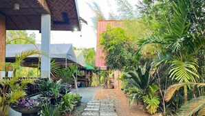 A pathway lined with potted plants leading to a building with a thatched roof. - Soulelle Villa with Pool (Silang)