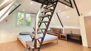 A loft bedroom with a wooden staircase, a bed, a desk, and a window. - Soulelle Villa with Pool (Silang)