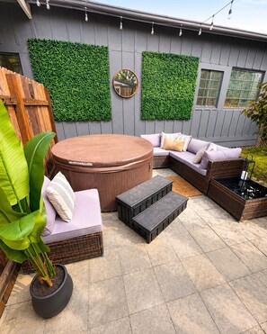 A patio area with a hot tub, seating, and a potted plant. - Eureka Nest: Fenced Yard + Hot Tub+Stylish and Pet Friendly (Eureka)