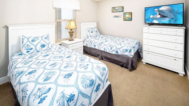 A bedroom with two beds, a television, a dresser, and a window with blinds. - Ariel Dunes II 1507 (Miramar Beach)