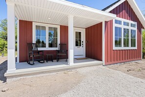 Ein rotes Gebäude mit Veranda, zwei Schaukelstühlen und einer Tür.