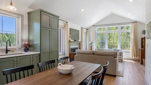 A kitchen with a dining table, chairs, and a large window. - The Cherry Cottages (Fish Creek)