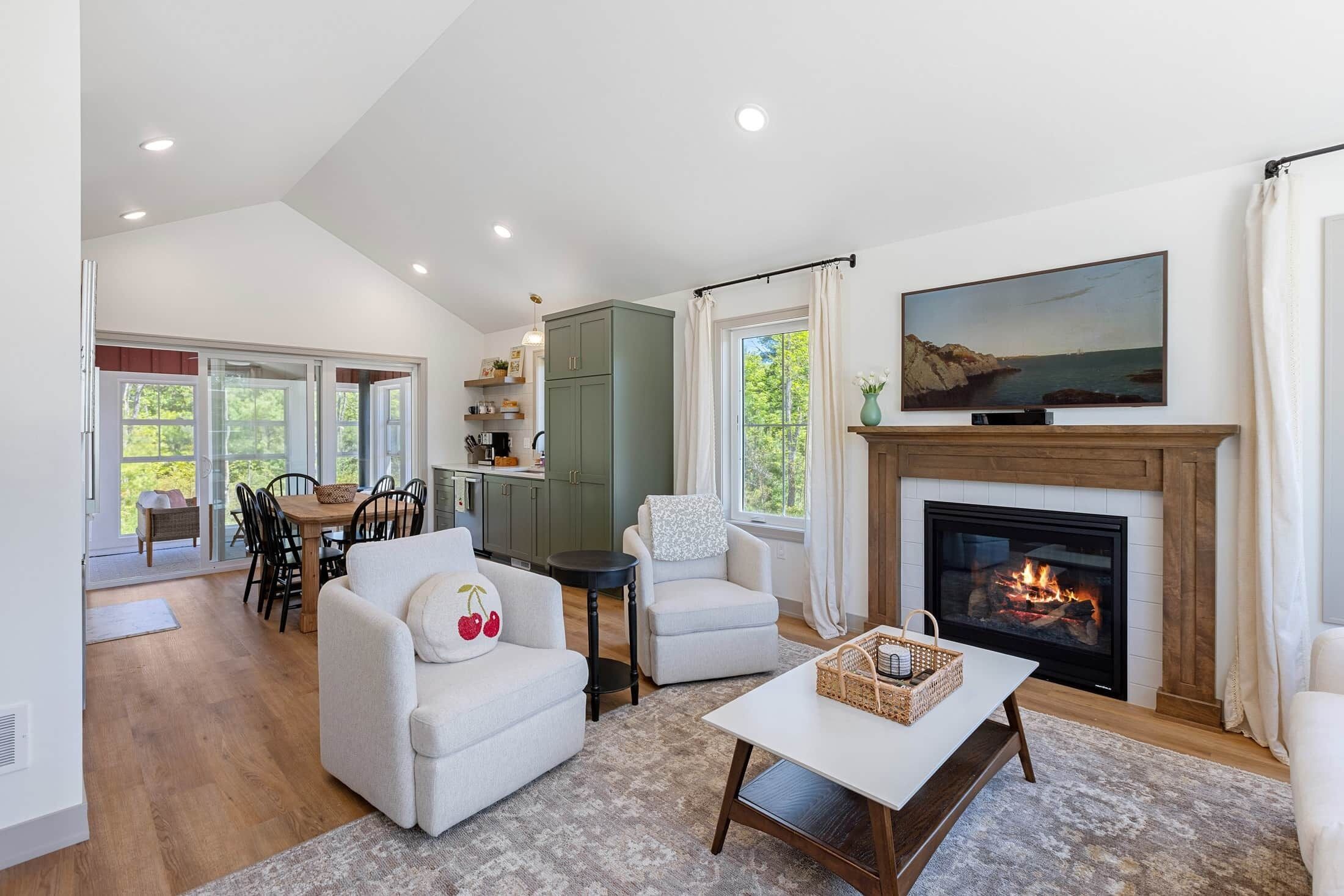 A living room with a fireplace, a dining area, and a kitchen.