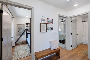 A hallway with a wooden bench, a staircase, and a bed in the background. - The Cherry Cottages (Fish Creek)