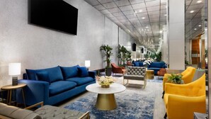A modern lobby with a blue sofa, a round coffee table, and yellow armchairs.