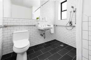 Un baño moderno con inodoro blanco, lavamanos y zona de ducha.