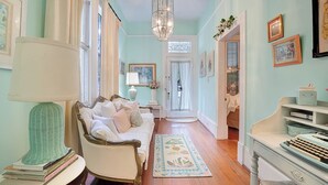 Um quarto aconchegante com um sofá antigo, uma mesinha com luminária e um tapete decorativo.