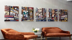 A room with two velvet armchairs, a small table with a vase, and a wall with a colorful comic strip mural. - Deluxe King | Walk to Times Square (New York)