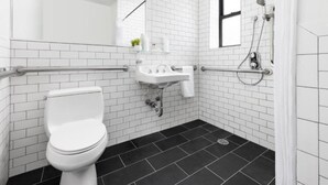 A modern bathroom with a white toilet, a sink, and a shower area. - Queen Room | Steps from Times Square (New York)