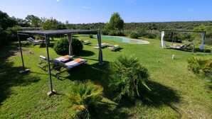 Een zwembadgedeelte met ligbedden, een pergola en uitzicht op een natuurlandschap.