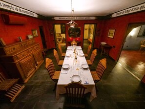 Comedor con una larga mesa dispuesta para una comida, sillas de madera y un aparador decorativo.