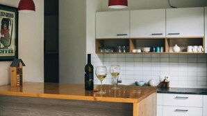 Una cocina con encimeras de madera, armarios blancos y lámparas colgantes rojas.