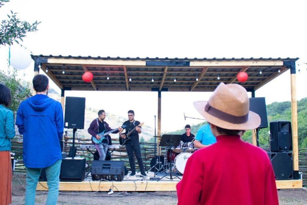 A stage with a band performing, surrounded by an audience.