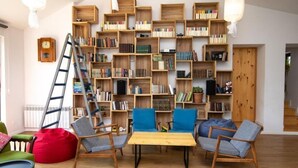 Una sala de estar acogedora con una estantería de madera llena de libros, una mesa de centro de madera y dos sillones azules.