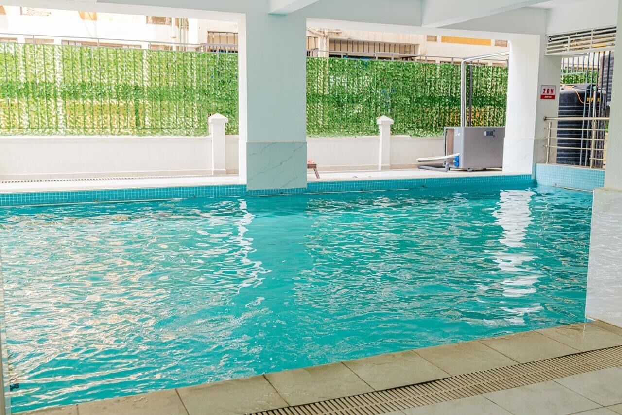 Una piscina interior con agua cristalina, rodeada de pilares blancos y suelo de baldosas.