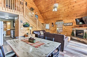 Ein Ferienhaus-Innenraum mit Essbereich, Kamin, Fernseher und einer Treppe.