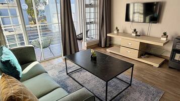 A modern living room with a sofa, a coffee table, a TV, and a sliding glass door.