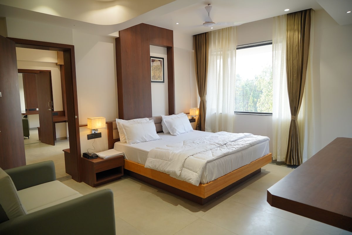 A hotel room with a large bed, bedside tables, a desk, and a chair.