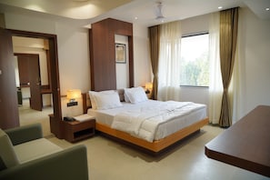 A hotel room with a large bed, bedside tables, a desk, and a chair. - Nayaks Sujay Murdeshwar (Murdeshwar)