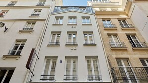 En byggnad med flera våningar i en klassisk arkitektonisk stil, med symmetriskt placerade fönster och balkonger.