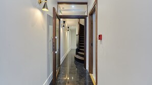 En modern hall med ett polerat marmorgolv, en trätrappa och moderna vägglampor.