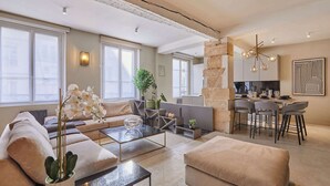 A modern living room with a sofa, coffee table, and a dining area with chairs and a kitchen in the background. - Superb duplex in the center of Paris (Paris)