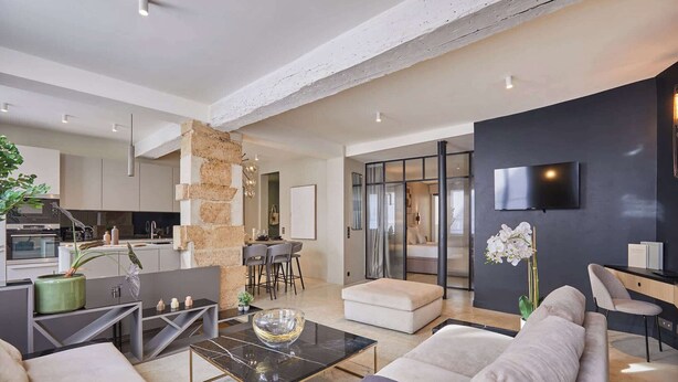 A modern living room with a sofa, coffee table, and a TV mounted on the wall. - Superb duplex in the center of Paris (Paris)