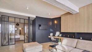 A modern living room with a sofa, a coffee table, a TV, and a dining area with a chair and a table. - Superb duplex in the center of Paris (Paris)