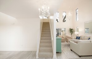 A spacious living area with a staircase, a large window, and a chandelier. - French Quarter Gateway Rental 320 Near New Orleans with Pool and Boat Dock (Slidell)