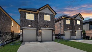 A residential area with brick houses, garage doors, and a well-maintained lawn. - Urban Townhome in Central Houston - near NRG Stadium! (Houston)