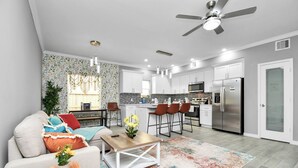 A modern kitchen with white cabinets, a stainless steel refrigerator, and a dining area with bar stools. - Urban Townhome in Central Houston - near NRG Stadium! (Houston)