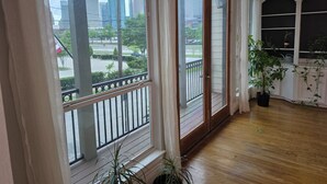 Une pièce dotée de grandes fenêtres, d’un plancher en bois et d’une plante en pot.