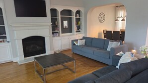 Un salon avec une cheminée, un canapé, une table basse et une bibliothèque.