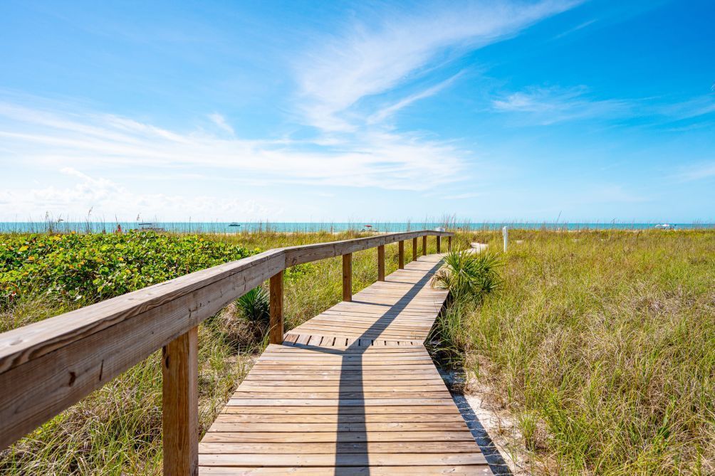 Une promenade en bois qui mène à une plage, avec un ciel dégagé.