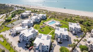 Ein Resort mit mehreren weißen Gebäuden, einem Schwimmbad und Blick auf den Strand.