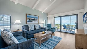 Ein Wohnzimmer mit einer Couch, Sesseln, einem Couchtisch und einem Balkon mit Sitzgelegenheit.