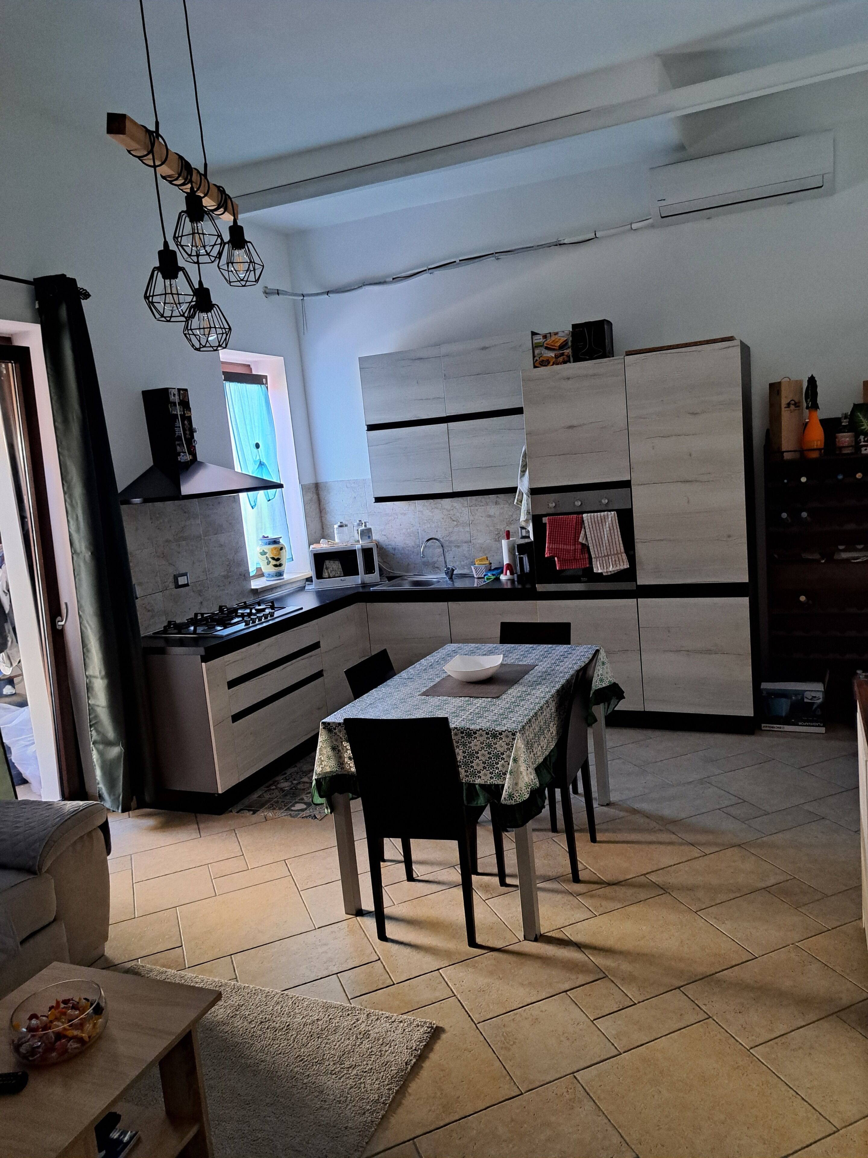 A modern kitchen with a dining area, a gas stove, cabinets, and a window.